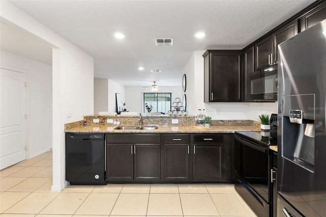 kitchen featuring sink, light stone countertops, light tile patterned flooring, black appliances, and dark brown cabinetry