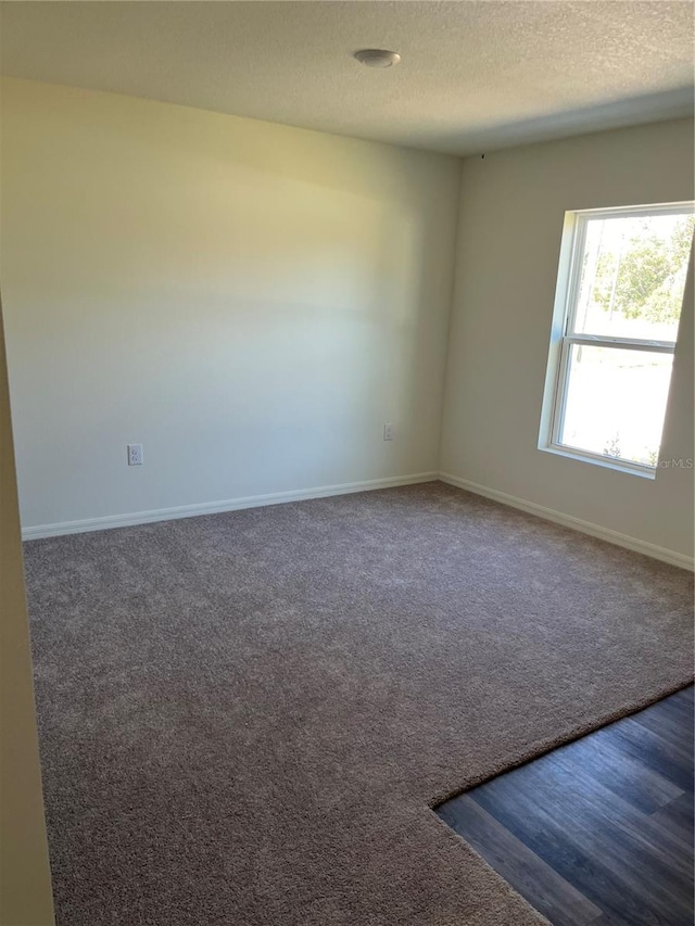 carpeted empty room featuring a textured ceiling