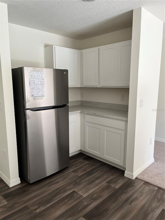 kitchen featuring white cabinetry, dark hardwood / wood-style floors, a textured ceiling, and stainless steel refrigerator