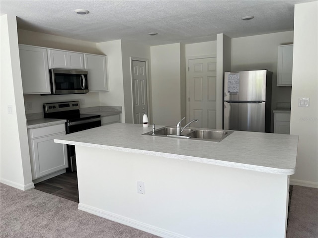 kitchen featuring white cabinets, appliances with stainless steel finishes, sink, and a kitchen island with sink