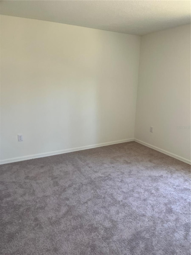 unfurnished room featuring dark carpet