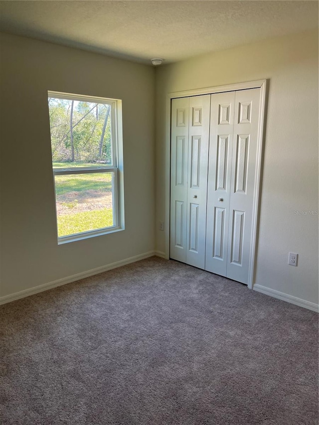 unfurnished bedroom featuring a closet, a textured ceiling, and carpet flooring