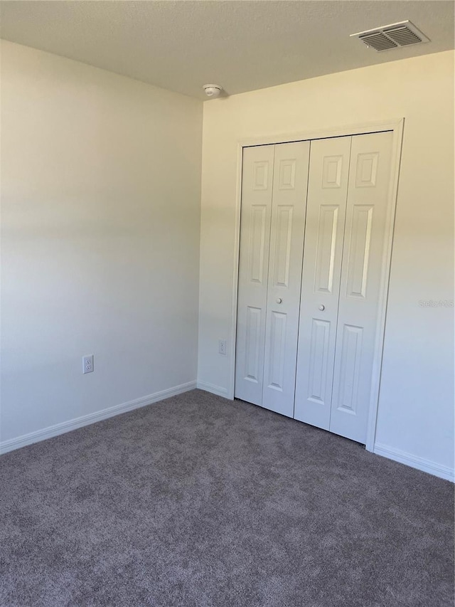 unfurnished bedroom with a closet and dark colored carpet