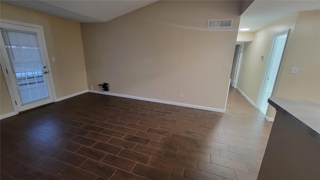 empty room featuring dark wood finished floors, baseboards, and visible vents
