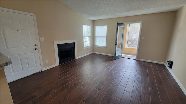 unfurnished living room with a textured ceiling and dark hardwood / wood-style flooring