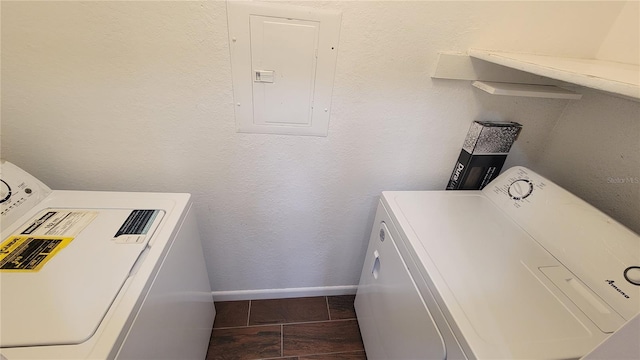 laundry area with electric panel, washer and dryer, and dark tile patterned flooring