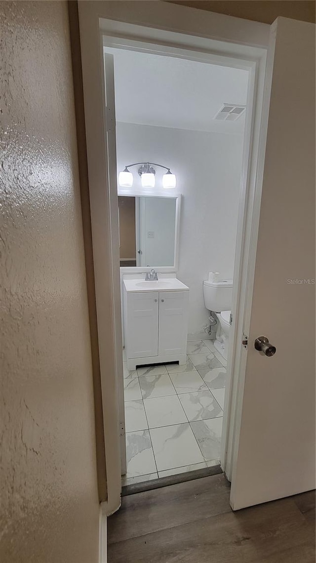 bathroom with vanity, toilet, and wood-type flooring