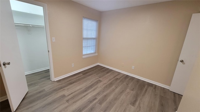 unfurnished bedroom with baseboards, wood finished floors, and a closet