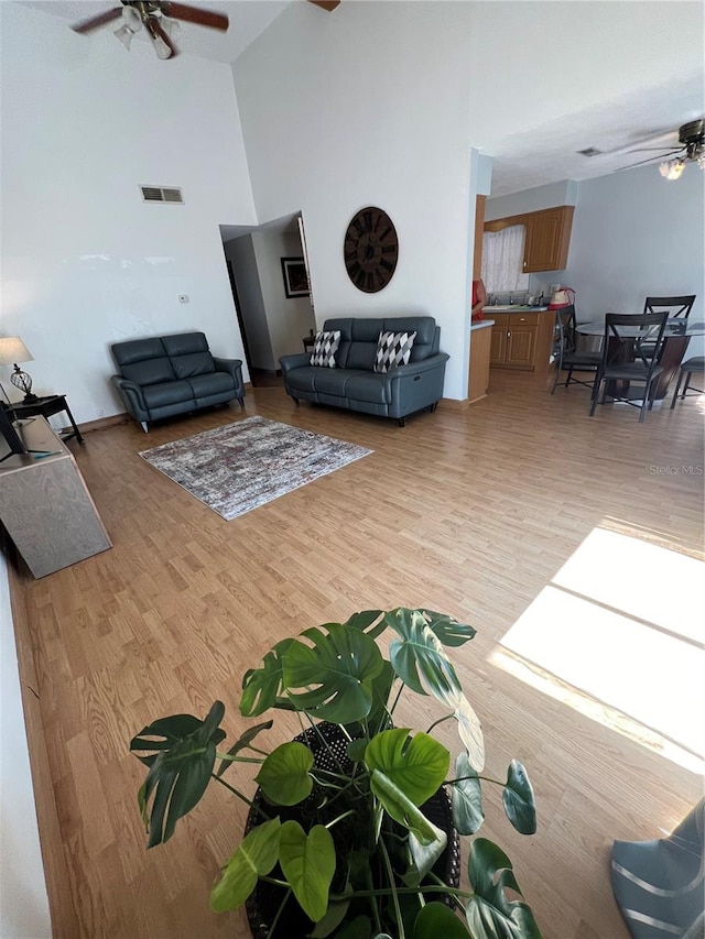 living room featuring high vaulted ceiling, light wood-type flooring, and ceiling fan