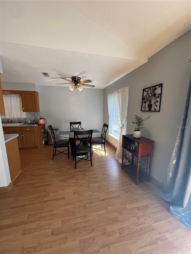 dining area featuring a textured ceiling, light wood-type flooring, and ceiling fan