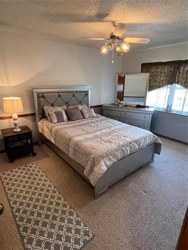 carpeted bedroom featuring ceiling fan and a textured ceiling