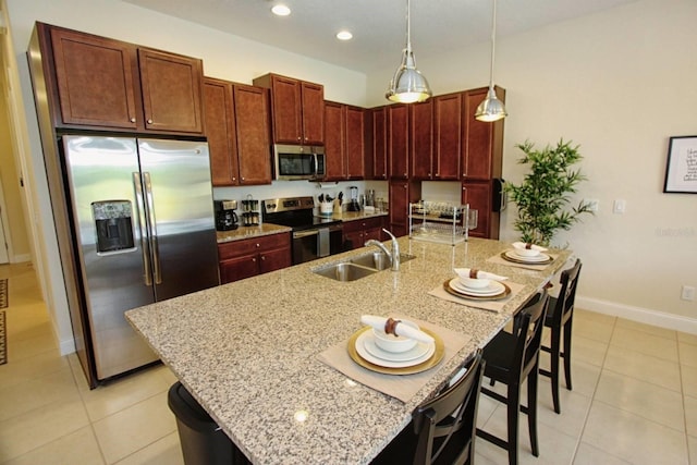 kitchen with a center island with sink, a breakfast bar, sink, pendant lighting, and stainless steel appliances