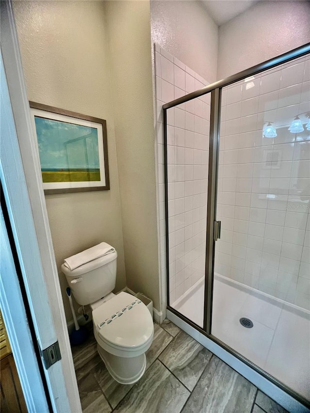 bathroom with toilet and a shower with shower door