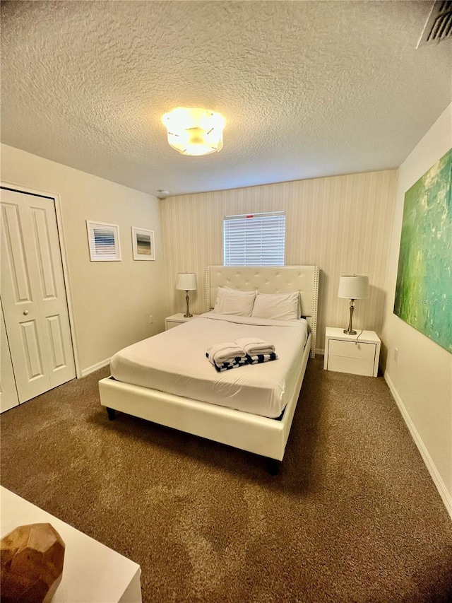 bedroom with a closet, a textured ceiling, and dark colored carpet