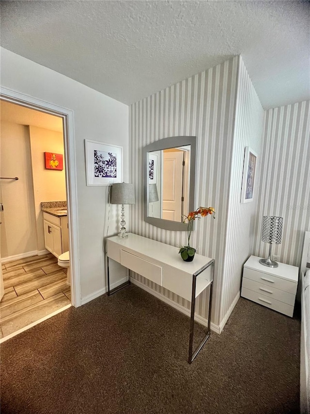 hallway featuring a textured ceiling and dark carpet