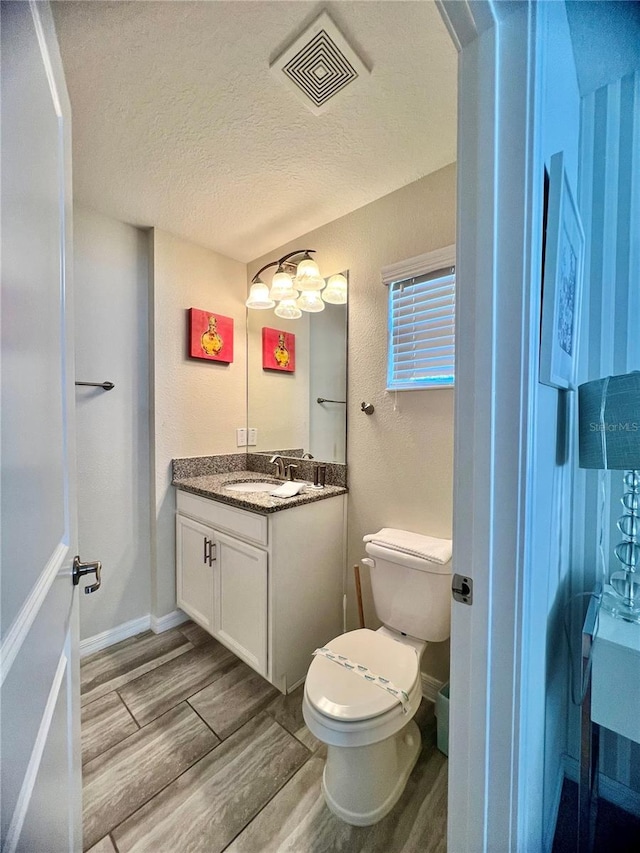 bathroom with vanity, hardwood / wood-style floors, a textured ceiling, and toilet