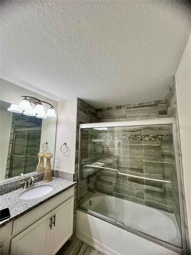 bathroom featuring vanity, hardwood / wood-style floors, enclosed tub / shower combo, and a textured ceiling