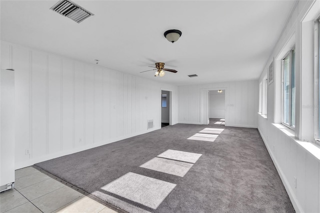 empty room with a ceiling fan, visible vents, and light colored carpet