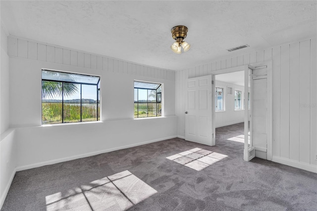 unfurnished bedroom featuring dark colored carpet, visible vents, a textured ceiling, and baseboards