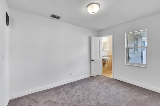 empty room with carpet flooring, visible vents, and baseboards