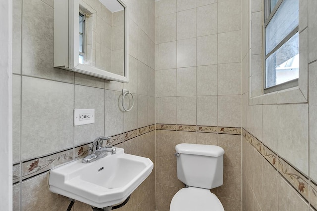 half bathroom with a sink, tile walls, and toilet