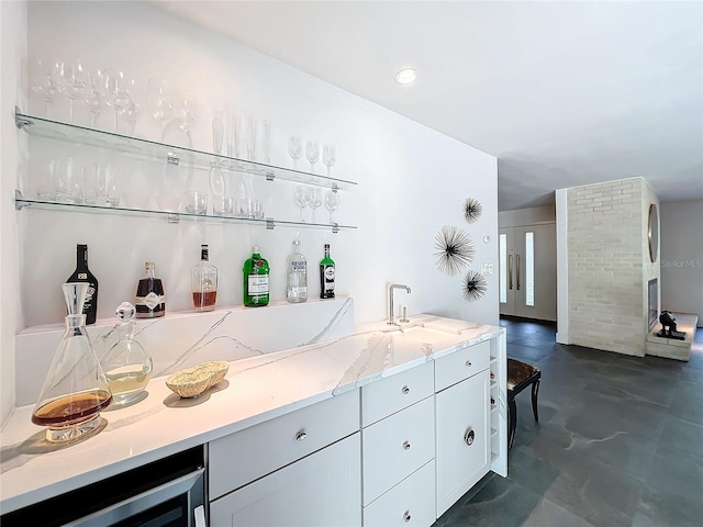 bar with light stone countertops, wine cooler, and sink