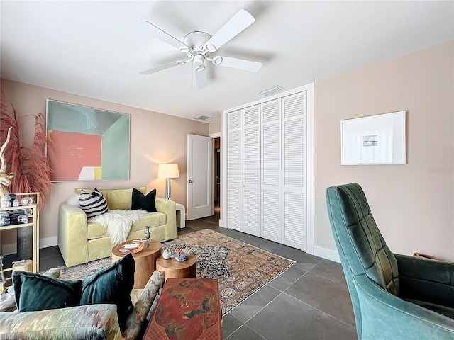 living room with ceiling fan and dark tile patterned floors