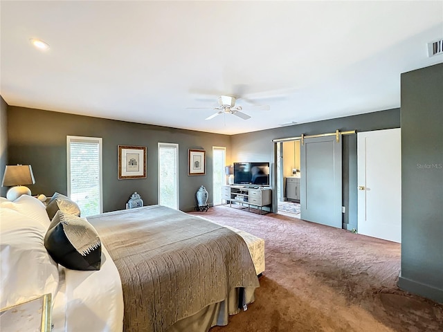 carpeted bedroom with ceiling fan and a barn door