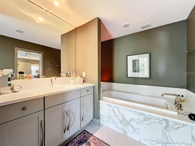 bathroom featuring tiled tub, tile patterned floors, and vanity