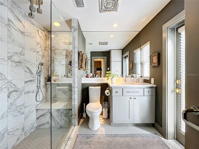 bathroom with tile patterned flooring, toilet, tiled shower, and vanity