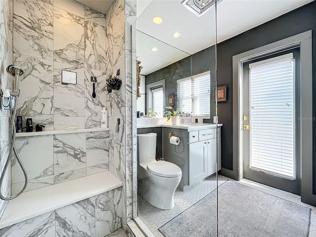 bathroom featuring toilet, vanity, and tiled shower