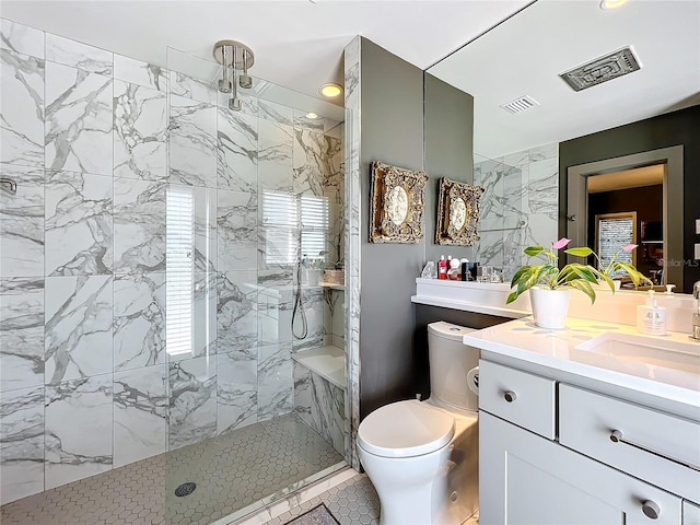 bathroom featuring a tile shower, vanity, tile patterned flooring, and toilet