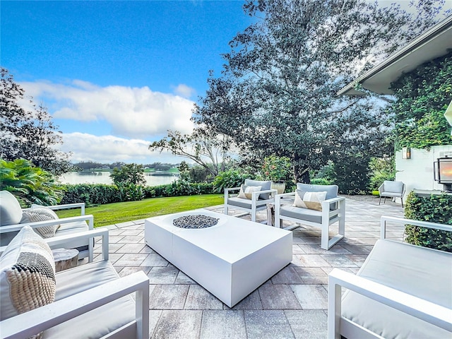 view of patio / terrace featuring a water view and an outdoor living space with a fire pit