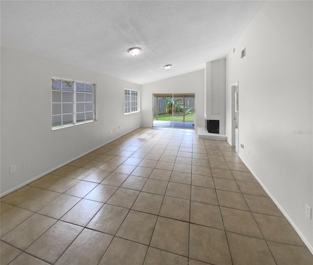 unfurnished living room featuring lofted ceiling, light tile patterned floors, and a textured ceiling