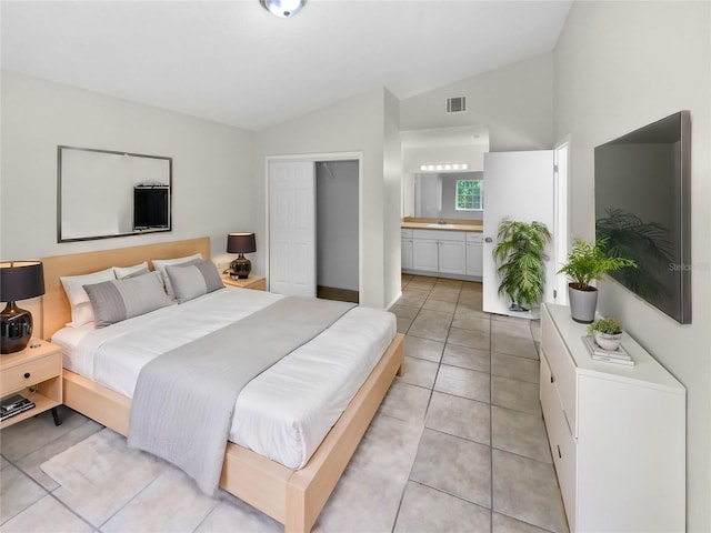 tiled bedroom with lofted ceiling, sink, a closet, and connected bathroom