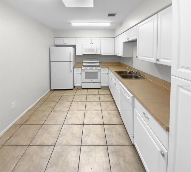 kitchen with light tile patterned flooring, white appliances, sink, and white cabinets