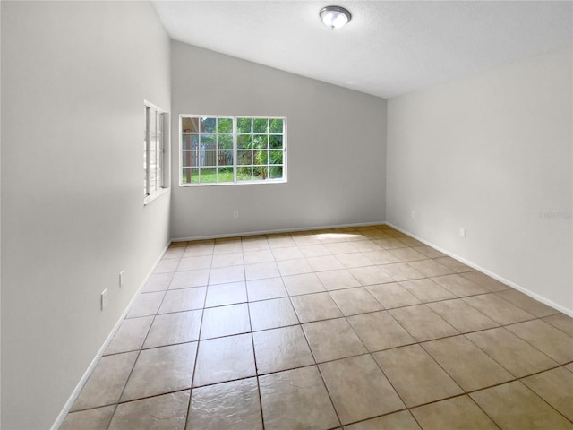 spare room with light tile patterned flooring and vaulted ceiling