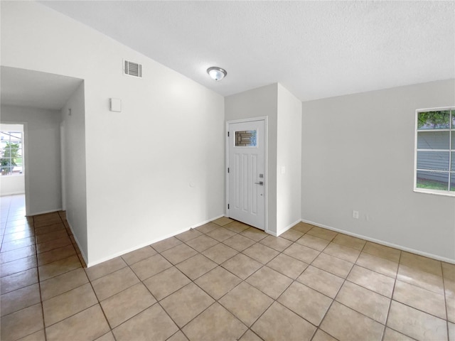 tiled entryway with a textured ceiling and vaulted ceiling