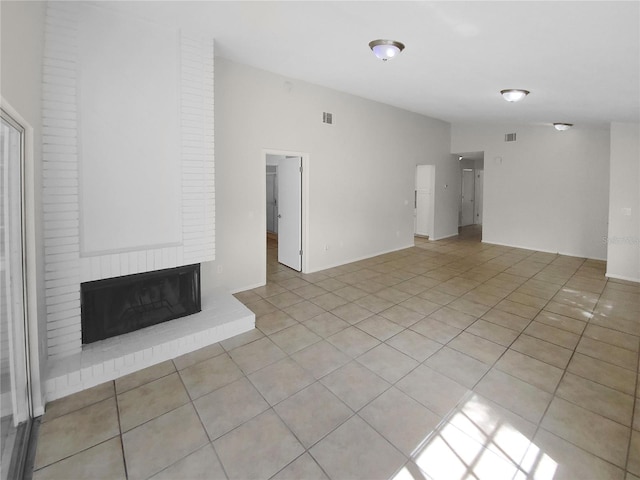 unfurnished living room with a brick fireplace and light tile patterned floors