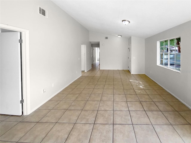 tiled spare room featuring vaulted ceiling