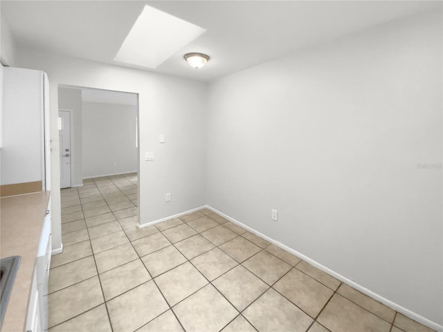 tiled empty room featuring a skylight