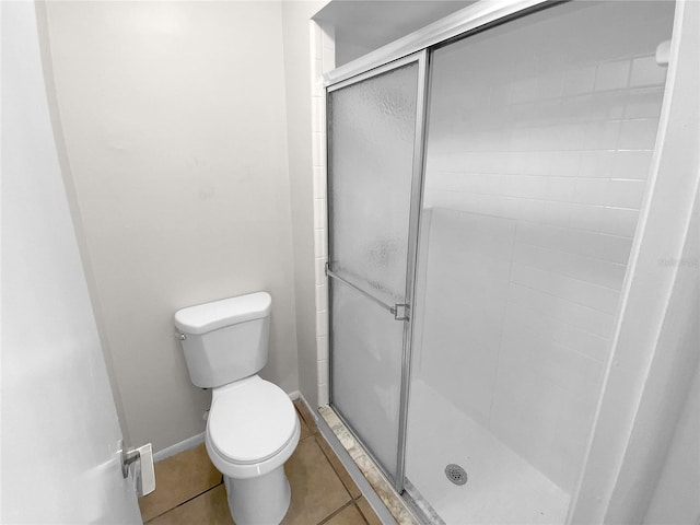 bathroom with tile patterned flooring, a shower with shower door, and toilet