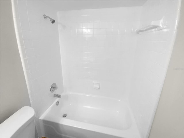 bathroom with tiled shower / bath combo and toilet