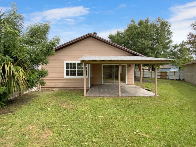 back of house with a lawn and a patio