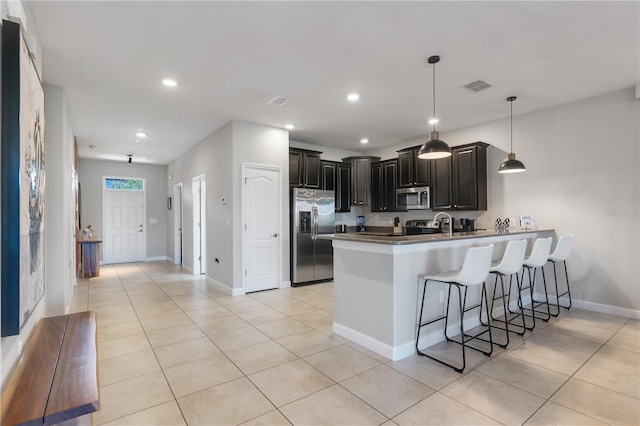 kitchen featuring kitchen peninsula, a breakfast bar, light tile patterned flooring, pendant lighting, and appliances with stainless steel finishes