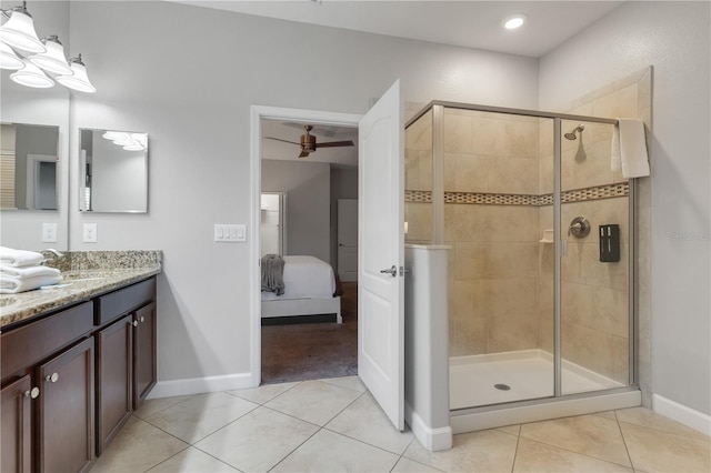 bathroom with a shower with door, vanity, and tile patterned floors