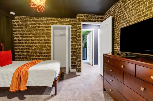 carpeted bedroom with a spacious closet, brick wall, and a closet