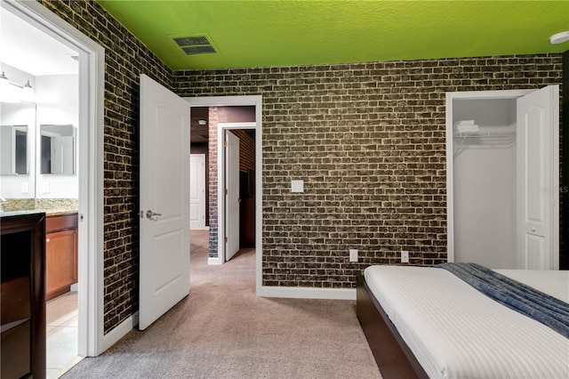 carpeted bedroom with a closet, brick wall, a textured ceiling, and a walk in closet