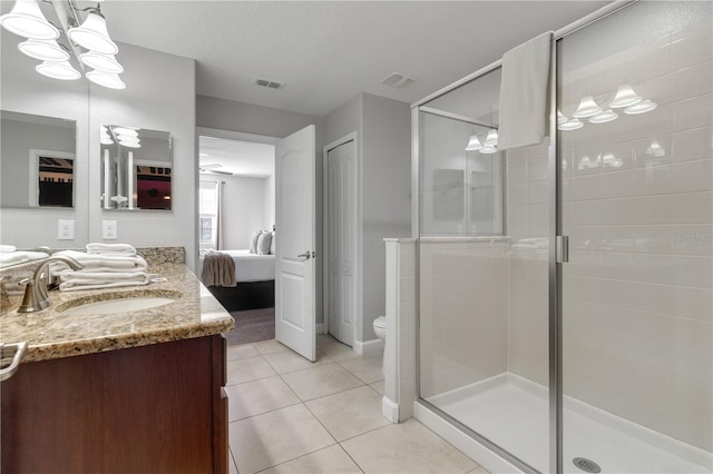 bathroom with a shower with door, vanity, toilet, and tile patterned floors