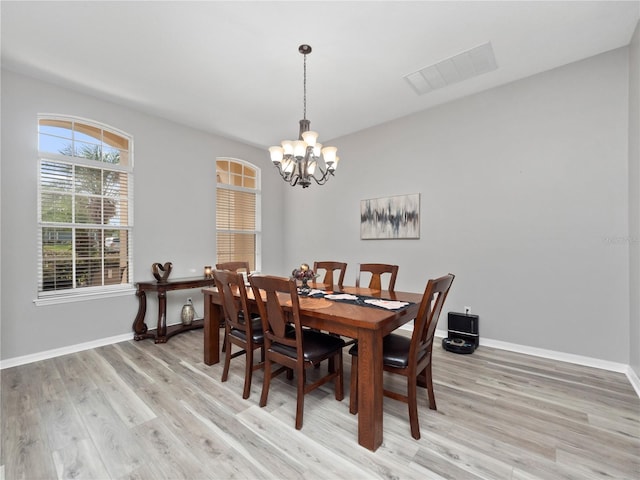 dining space featuring light hardwood / wood-style floors and a notable chandelier